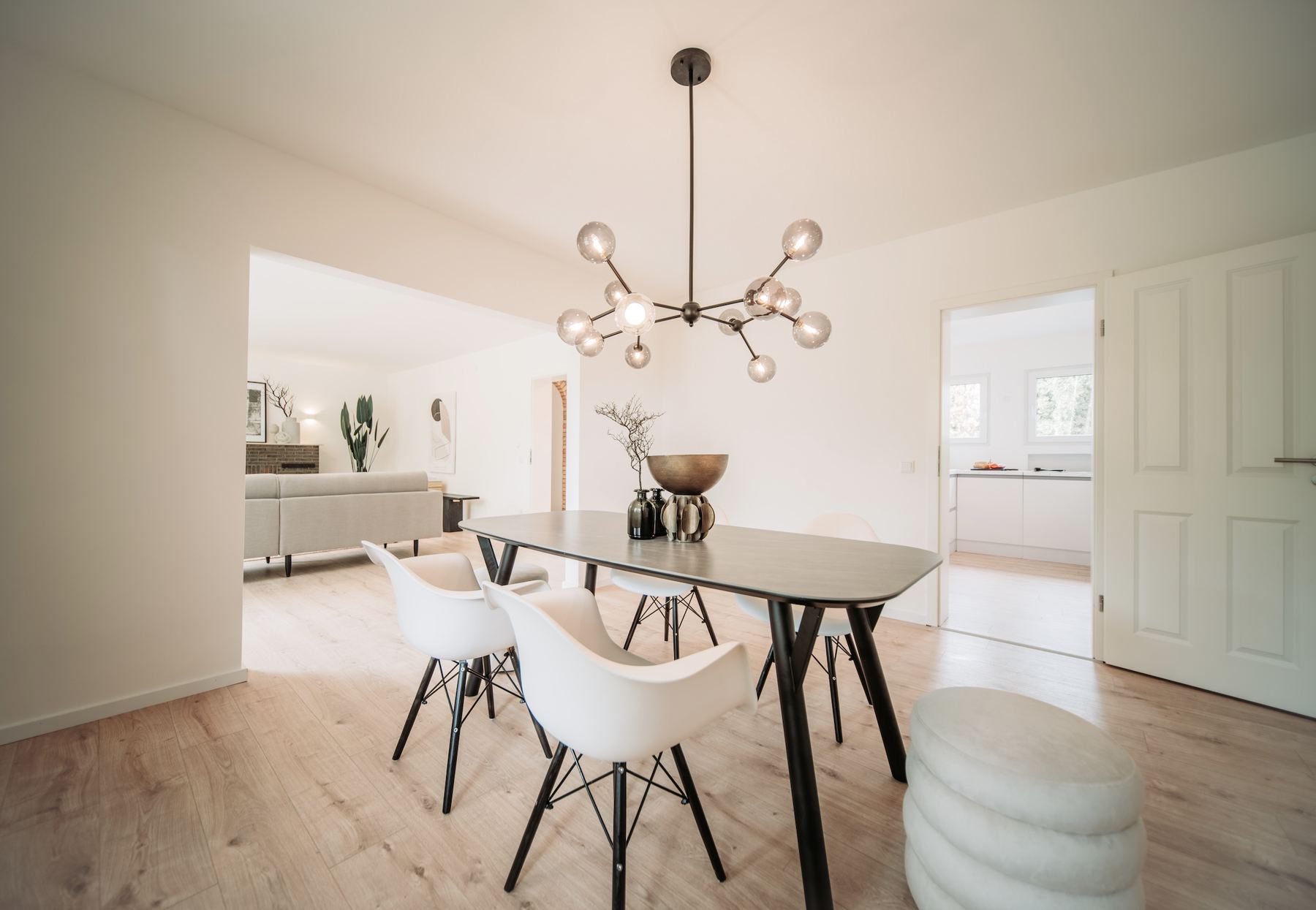 Essbereich mit Holztisch, weißen Stühlen und Pendelleuchte, Blick ins Wohnzimmer